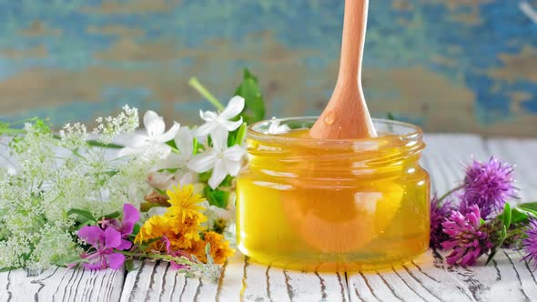 Honey in Glass Jar with Honey Dipper Over Rustic Wooden Background