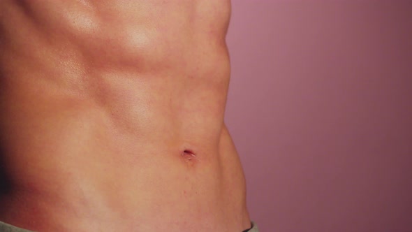 Male Body with Inflated Abs Closeup on Pink Background