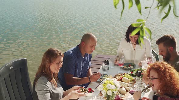 Slow motion shot of friends having dinner on jetty at lake