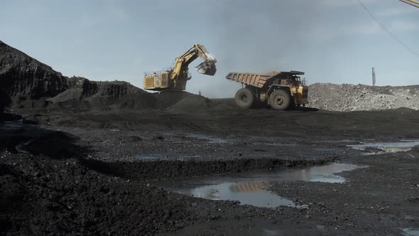 Giant Dump Truck is Reversing Towards an Excavator