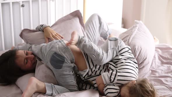 Happy Mother is Playing Together with Her Two Daughters in Bed Making Mess in Slow Motion