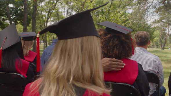 Diverse Proud Parents Embracing Multiracial Graduates at Graduation Ceremony