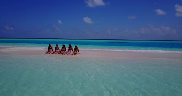 Modern smiling girls travelling by the sea on beach on clean white sand and blue background 4K