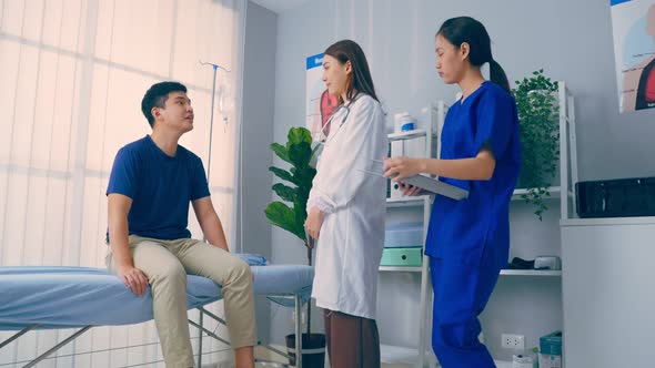 Asian specialist doctor and assistant nurse take care of male patient.