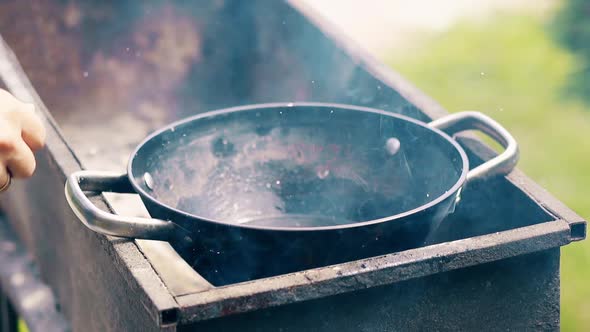 Close-up, Slow Motion: Oil Boils in Cauldron, on the Coals, on the Grill