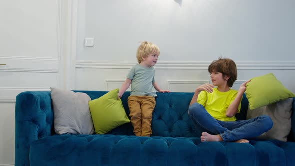Little Blond Boy and His Brother Fight with Pillows at Home