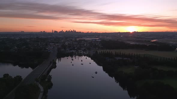 Aerial view of the skyline in the suburb of Sydney with cityscape in the silhouette, during sunrise.