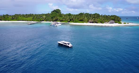 Island In Hawaii - Lush Island And White Sand Surrounded By Deep Blue Sea Water With Boats Floating