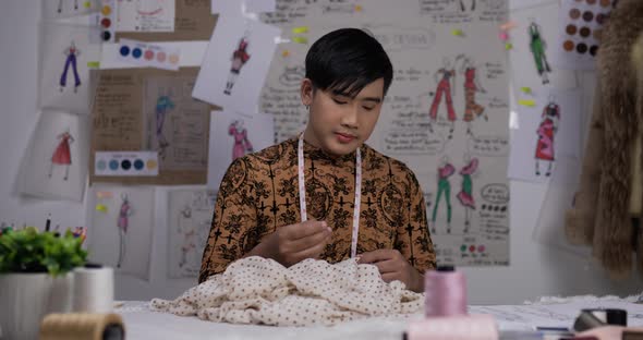 Sleepy fashion designer man sewing in studio