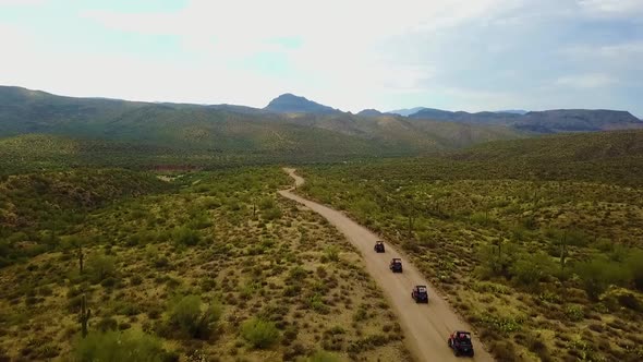 Aerial drone shot of four UTV's driving through the Arizona desert on a cloudy day