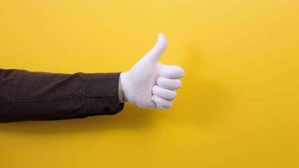 A male's hand in a shirt and white glove shows a thumbs-up gesture.