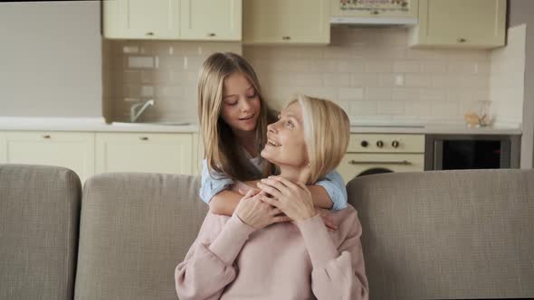 Little Girl Hugging Her Grandmother Sitting on the Couch