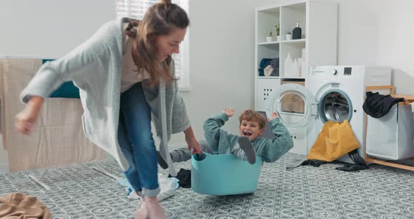 Mom is Playing with Son Who is Sitting in Laundry Bowl Little Boy Wants to Spend Time with Woman and