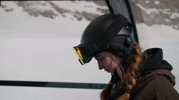 Woman With Red Plaits In Skiing Helmet In Cable Car