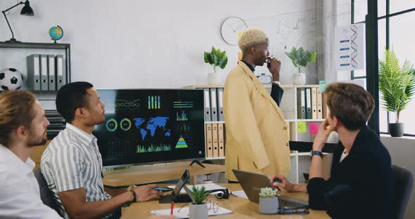 Male Work Team Sitting in Office Room and Listening Explanation from African American Colleague