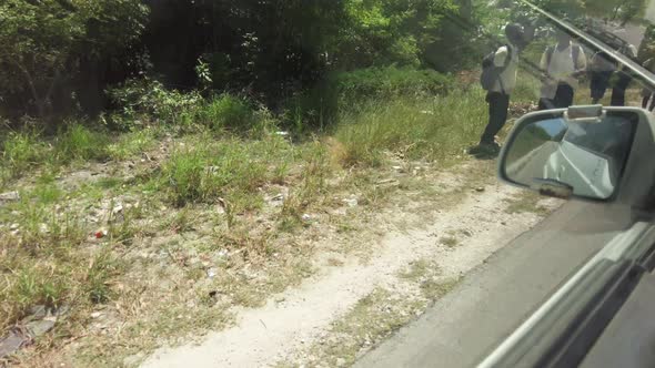 View From Car of Local African Schoolchildren Walking Along the Road By Village