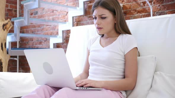 Young Woman Upset by Loss while Working on Laptop