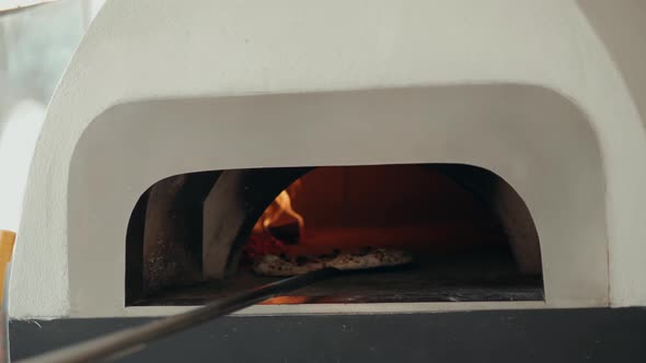 Chef in the Pizzeria Prepares a Pizza and Decorates It with Parmesan Cheese Pepper and Basil