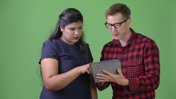 Young Multi-ethnic Business Couple Together Against Green Background