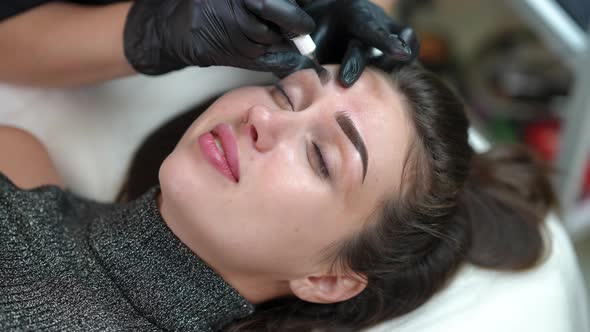 High Angle View Portrait of Caucasian Woman Doing Permanent Makeup with Unrecognizable Beautician