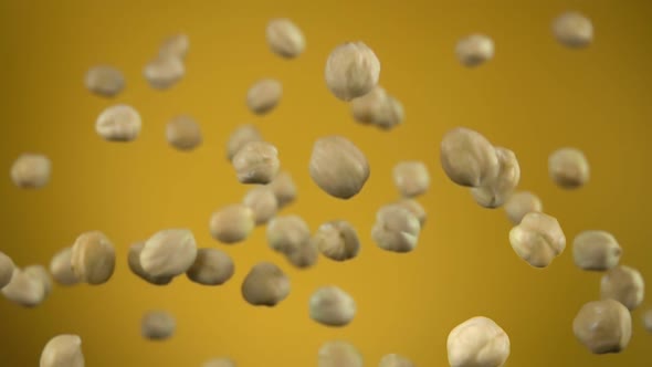 Close Up of Hazelnuts Flying Up on the Yellow Background