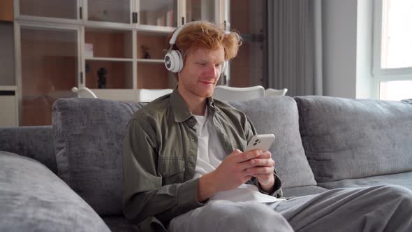 Young Irish Ginger Man in Headphone Doing Video Call Using Smartphone