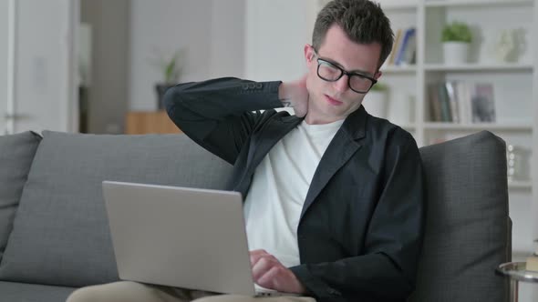 Tired Young Male Designer with Laptop Having Neck Pain at Home