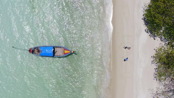 Aerial drone shot flying above lipe island beach with wood long tail boat, South of thailand.