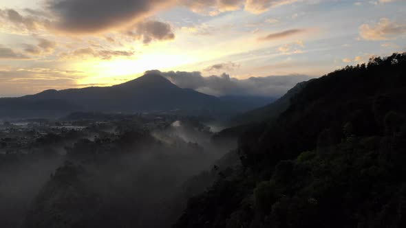 Aerial view of sunrise at mountain top with fog and clouds down in the mountain valley