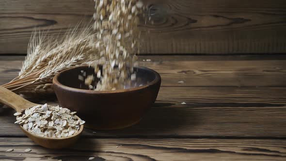 tmeal falling into a bowl on a wooden table. Healthy lifestyle concept