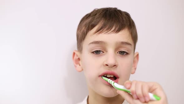 Little boy brushing his teeth on a white background