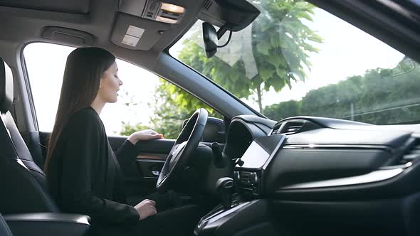 Successful Young Caucasian Businesswoman Sitting in New Car on Parking Beside Dealership