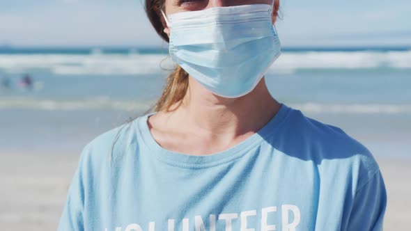 Portrait of caucasian woman wearing volunteer t shirt and face mask looking at camera