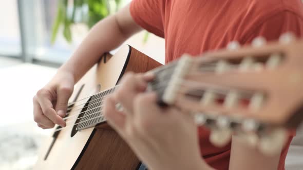 Portrait of a Handsome Boy Sitting on the Couch and Playing the Guitar