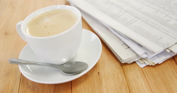 Coffee and newspaper on wooden plank