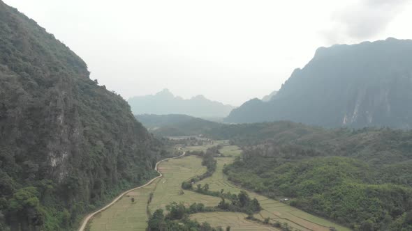 Aerial: flying over scenic cliffs rock pinnacles tropical jungle rice paddies