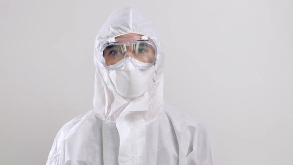 Confident Asian doctor in protective PPE suit wearing face mask and eyeglasses