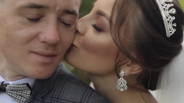 Newlyweds. Caucasian Groom with Bride. Making a Kiss in Park. Happy Wedding Family Couple