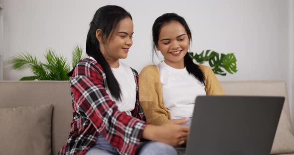 Asian twin girls playing smartphone on phone and using laptop