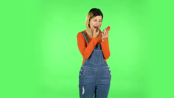 Girl Paints Her Lips Looking in Red Mirror. Green Screen