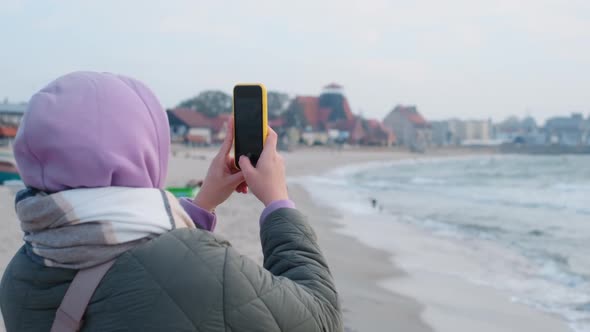 Woman Blogger in Warm Clothes Does Selphie on the Winter Beach