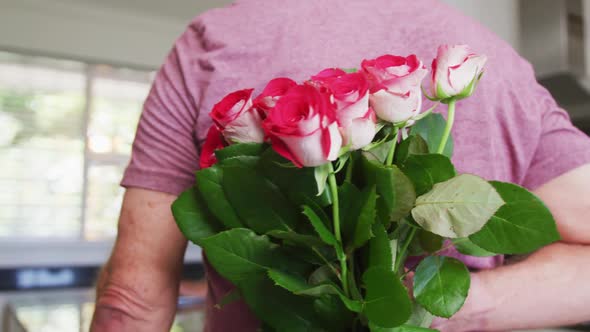 Caucasian senior man giving a flower bouquet to his wife at home