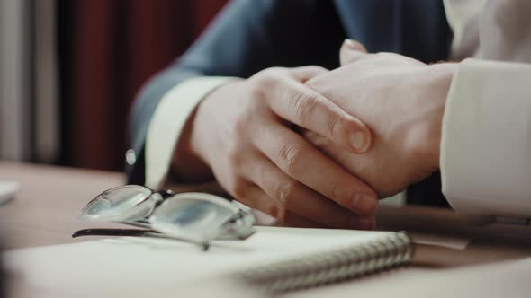 Business Concept  Closeup of Handsome Mature Businessman Hands Near Copybook and Glasses