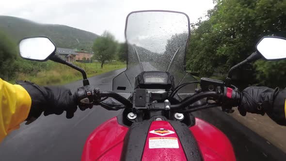 Motorcyclist on Bike Rides on a Landscape Mountain Road in the Rain