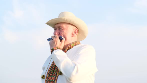 Portrait of an Elderly Ukrainian Man in an Embroidered Jacket Playing the Harmonica