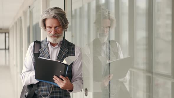 Mature Businessman in Suit Reading in the Airport Terminal