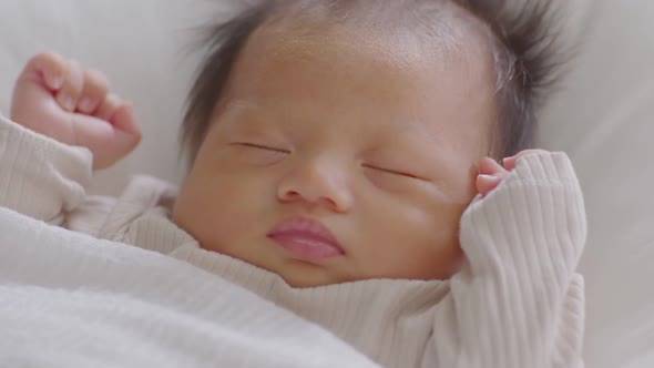 Close up happy newborn baby lying sleeps on a white blanket comfortable and safety