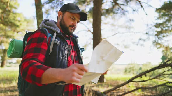 Traveler Stand in Forest and Look at Map in Hands and Looks for Way