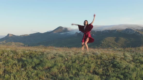 Mystical Dance Performed By a Sexy Woman in a Red Dress on a Hilltop in the Rays of the Sunset