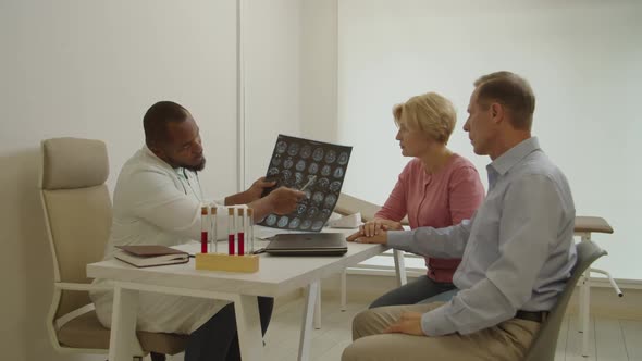 Black Man Doctor with Mri Scan Explaining Test Results to Worried Ill Middle Aged Man at Hospital